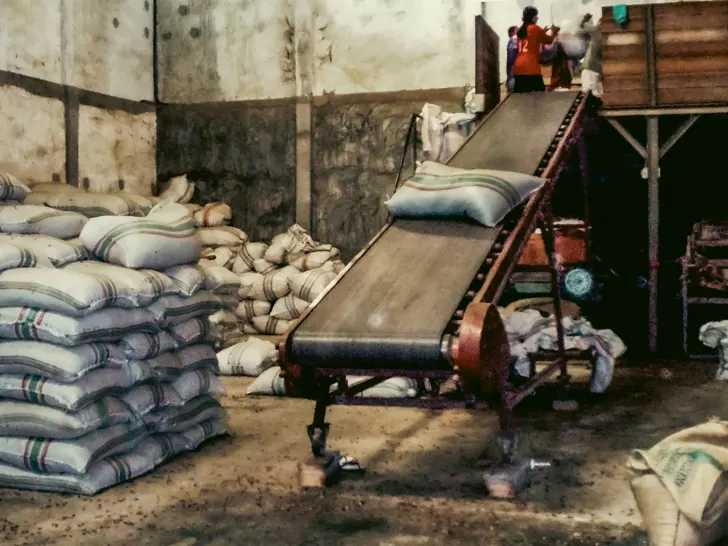 Stacked woven sacks and a loading conveyor in a warehouse