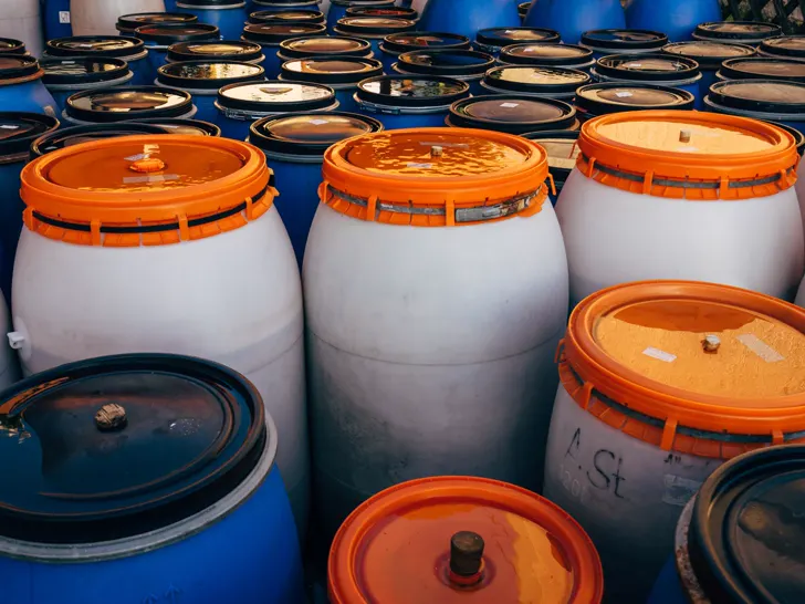 White plastic drums with orange lids, stacked in rows